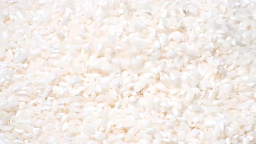 White Uncooked Rice Crumbles and Rotates in a Circle Cooking in China