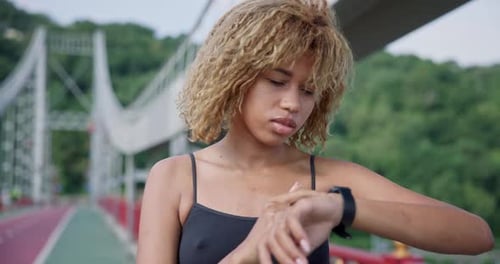 Sporty African American Woman Looking at Her Sport Bracelet on Hand Checking Data on Fitness Tracker