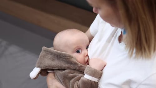 Mother in White Shirt Breastfeeding in in Public Area