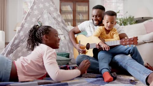 Man Playing Guitar with Children in Living Room