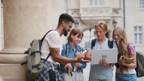University students collaborate on project outside campus building on sunny day