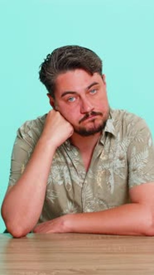Man Sitting at Table Supporting Head with Hand Staring Blankly Feeling Emotional Burnout and Apathy