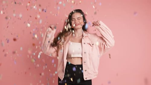 Woman Dancing in Confetti Shower on Pink Background