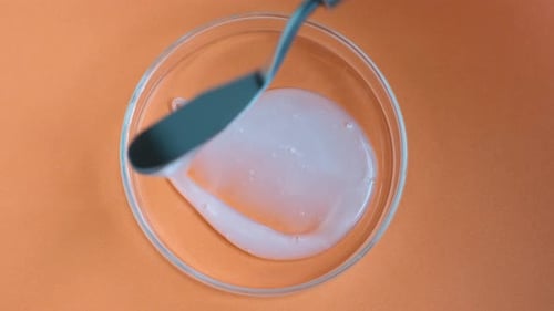 Étaler du gel douche ou du shampoing dans une boîte de Pétri sur fond orange.
