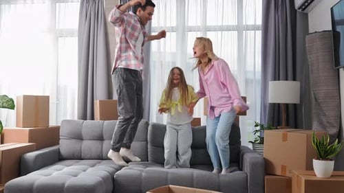 Energetic Family Jumping on Sofa in New Home
