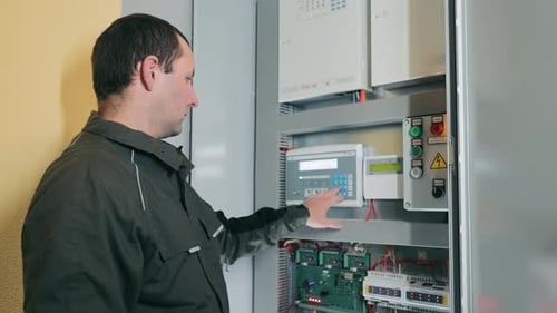Technician Operating Electrical Control Panel Male Technician Adjusting Settings on an Industrial