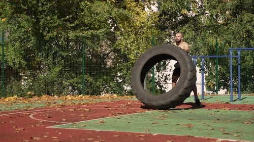 Shirtless Man Doing Tire Flip Workout Outdoors