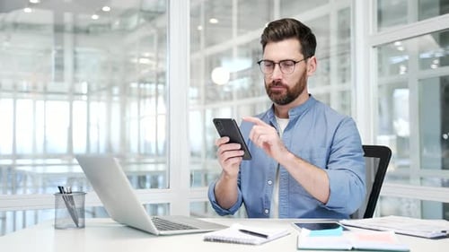 Man at desk using phone in modern office