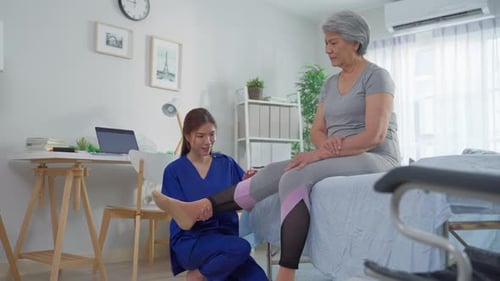 Caring Woman Doing Leg Therapy for Senior Woman