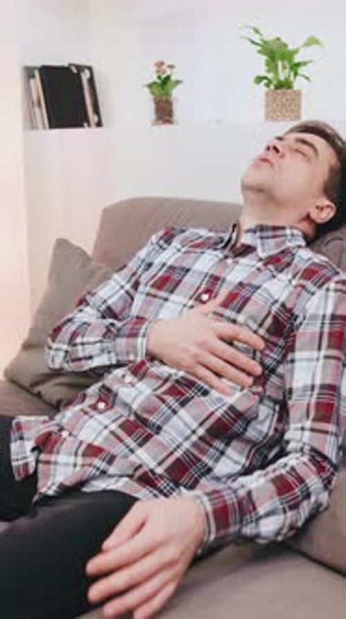 Man Lying on Couch Holding Chest