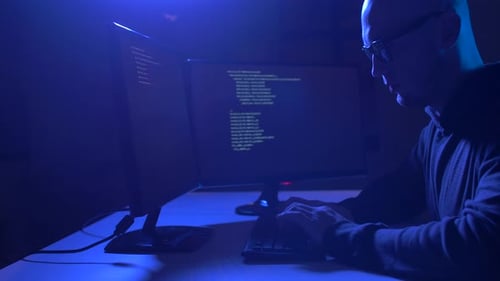 Man Working at Computer in Dark Blue Lit Room