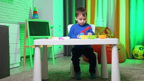 Child Playing with Plasticine at Table Indoors