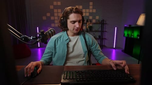 Young Adult Streamer Using Computer and Wearing Headset
