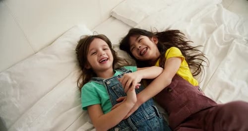 Girl Friends or Children on White Bed While Relax Together and Play Top View