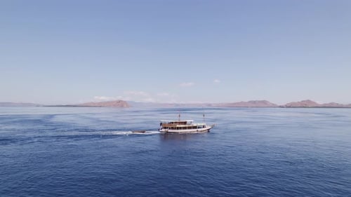 Crucero turístico que viaja en el océano azul cerca de la isla de Komodo en órbita aérea distante