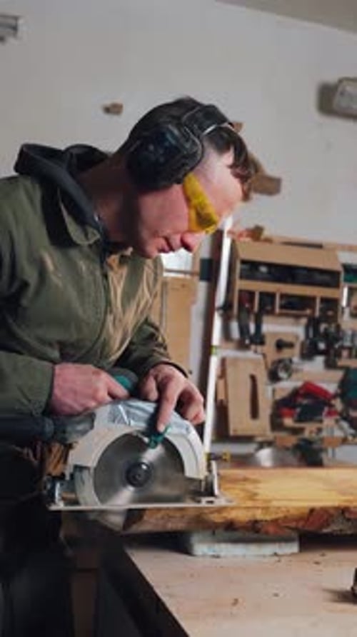 Man Cutting Wood with Circular Saw in Workshop