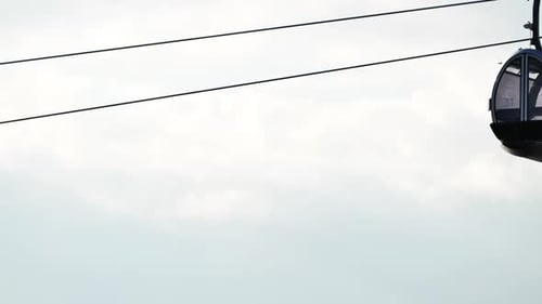 Two Modern Cable Car Gondolas Suspended Against a Pale Overcast Sky