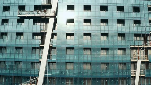 Fassade eines modernen mehrstöckigen Glasgebäudes im Bau mit Kran auf der obersten Konstruktion