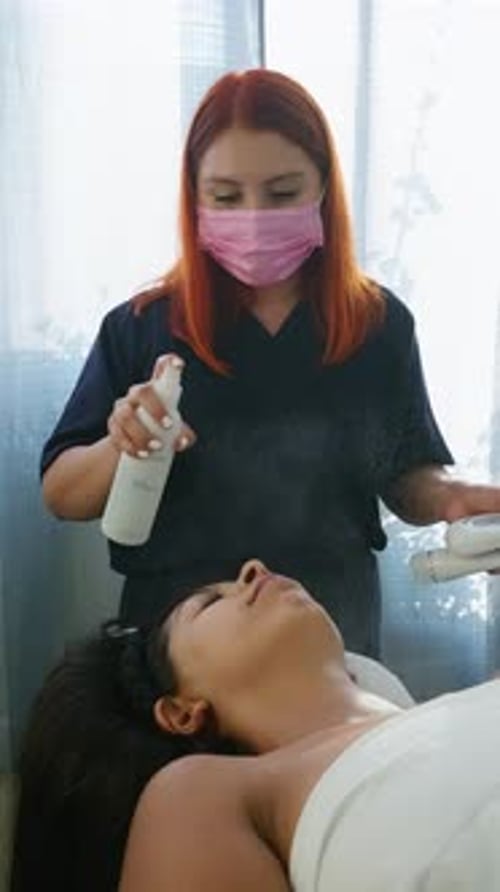 Esteticista pulverizando névoa hidratante no rosto de uma mulher