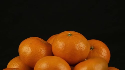 Isoliertes Essen: Ein Haufen von Orangen dreht sich vor schwarzem Hintergrund