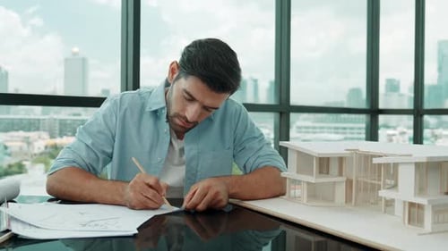 Architect Working on Blueprints and Model in Office