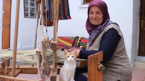 Senior Woman Weaving with Cat in Rural Setting