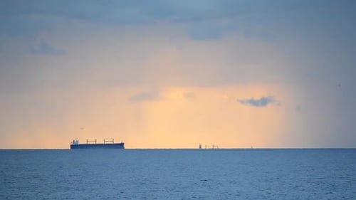 A Graincarrier Tanker is Far Away on the Horizon Line in the Sea on Background