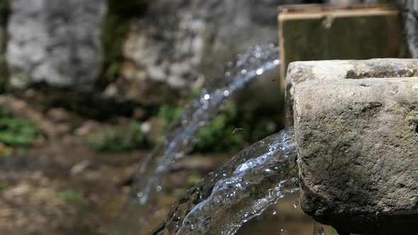 Woman washing hands with running spring water at an old water source ...