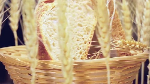 Wicker Basket with Sliced Bread and Ears of Wheat Around it