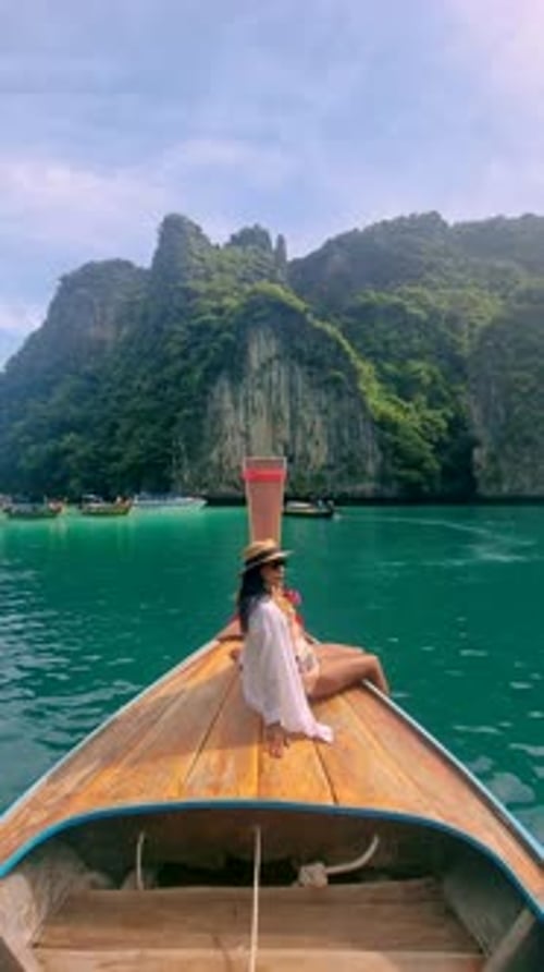 Asian Women in Front of Longtail Boat with Green Blue Turqouse Lagoon at Koh Phi Phi Thailand