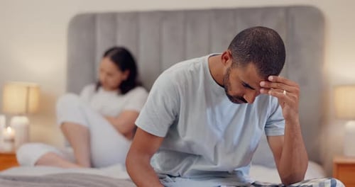 Upset Man and Woman Sitting on Bed