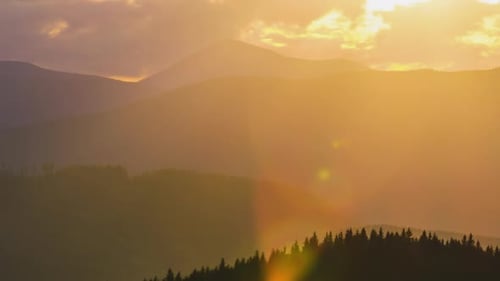 Beautiful Evening Panoramic Landscape with Bright Setting Sun Over Distant Mountain Peaks at Sunset