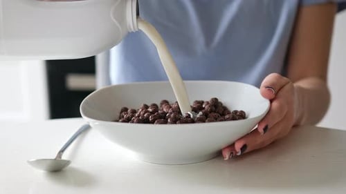Pouring Milk over Chocolate Cereal at Breakfast