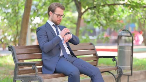 Man in Suit Checking Smartwatch on Park Bench