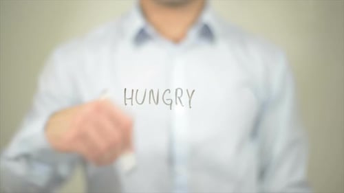 Man Writing Hungry on a Clear Surface