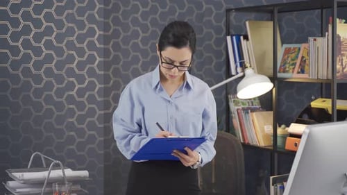 Worker woman looking at computer and taking notes works in office.