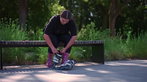 young hipster girl puts on roller skates in skate park before starting skating street extreme sport