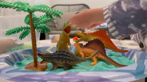 Enfant jouant avec des mini-figurines de dinosaure.