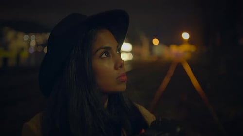 Woman Photographer Holding Camera in Urban Night Scene