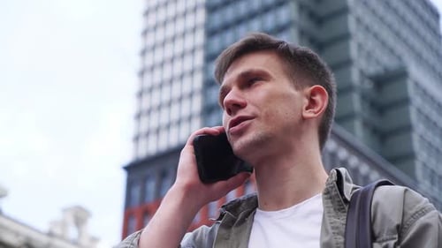 A young man talking on the phone. A busy city street