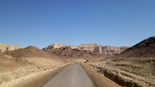 Empty desert road with mountains and blue sky in the background