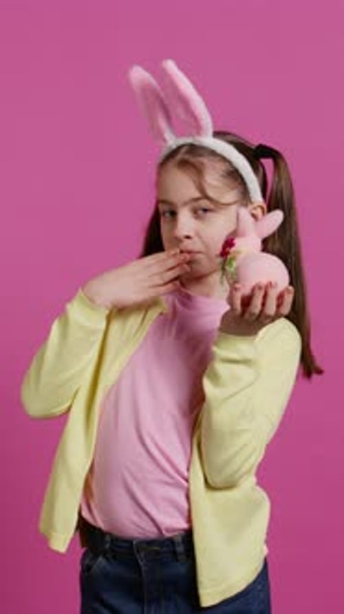 Jolly Schoolgirl Holding a Cute Rabbit Toy and Blowing Kisses in Studio