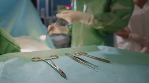 Close-Up of Hands Passing Surgical Instruments to Surgeon
