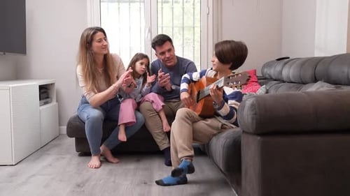 Family Cheering for Boy Playing Guitar