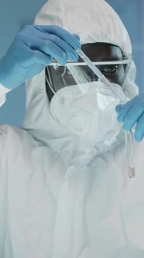 Scientist in Protective Suit Holding Fluid Vial