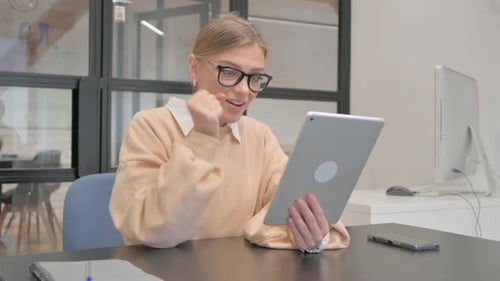 Female Worker Celebrating Success on Tablet in Office