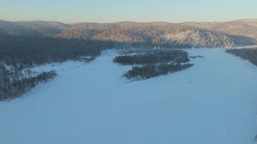 Enjoy the Stunning Aerial View of a Snowcovered River and Forest in a Serene Winter Landscape