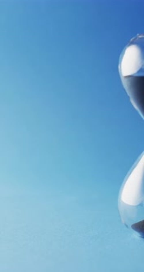 Hourglass with Sand Falling on Blue Background