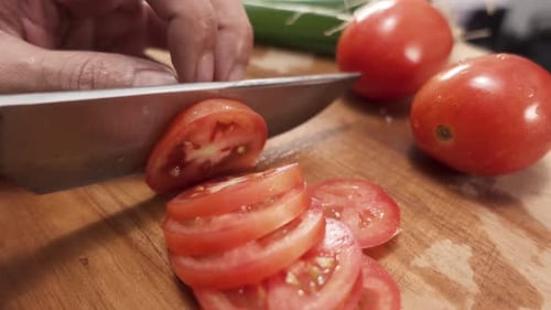 Slicing Ripe Red Tomato on Wooden Cutting Board