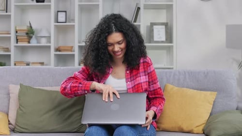Young Woman Opens Laptop on Couch at Home